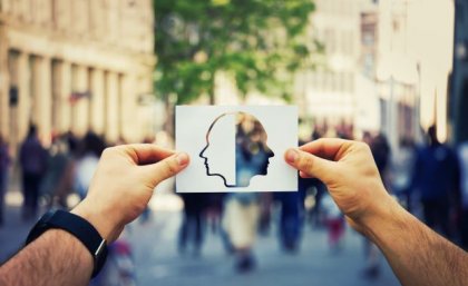 A man's hands holding a picture of the side profile of two faces. Adobe